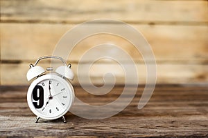 Clock at 7 O`clock in the morning with vintage style alarm clock on a wooden table