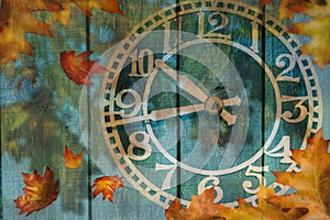 Clock and autumn leaves background - daylight saving time concept