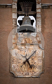 A clock and a bell on an old stone tower