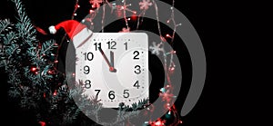 Clock in branches of New Year`s fir on black background. Second hand moves in circle of mechanical clock and show Twelve o`clock a