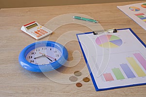 Clock, calculator, pen, graphics on table, small change. business accounting concept, financial flows