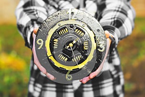 A clock from a car clutch disc. Black watch with gold elements. Man holding a clock in his hands