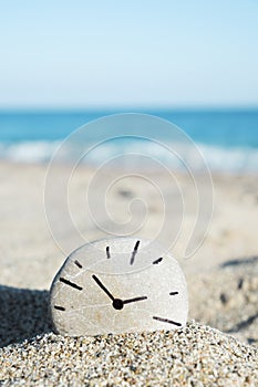 Clock drawn on a stone, on the sand of a beach