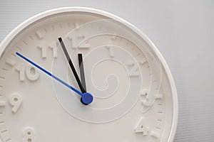 Clock face showing twelve o`clock with white background. White round wall clock. Twelve o`clock. Midday or midnight. 12 a.m. or