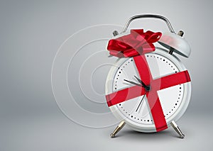 Clock in gift ribbon on grey, time to gift cocept, copy space.