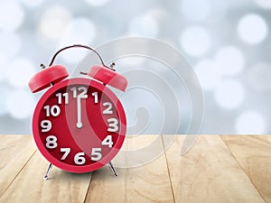 clock hand point to minute before midnight on retro red alarm clock on table top and blurred lights bokeh background