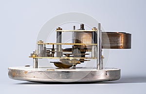 Clock lying on dial with open clockwork on an isolated gray studio background. Clockwork mechanism with gears, cogwheel