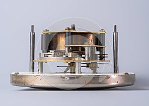 Clock lying on dial with open clockwork on an isolated gray studio background. Clockwork mechanism with gears, cogwheel