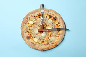 Clock made of pizza and cutlery on blue background