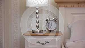 Clock and night light on bedside table, hand take the clock, vintage bedroom