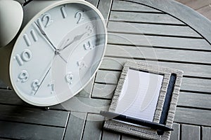 Clock and notebook on wooden table.