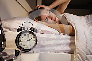 Clock show 2 O`clock and woman sleepless on bed