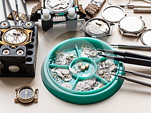 clock spare parts in tray and old watches on table