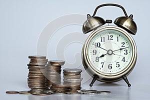 A clock and stack of coin on white background. Savings and investment plan concept. Time and money concept