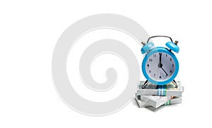 A clock is standing on a bunch of packs of money on a white background. The concept of expressing time is money. Planning time