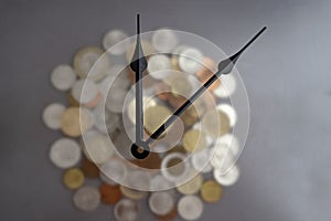 clock tongues over blurred pile of coins, time is money