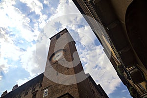 Clock tower framed by a building with a cloudy sky as background