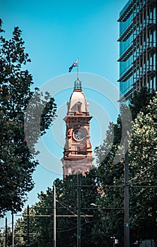 a clock tower in the middle of a city street near trees