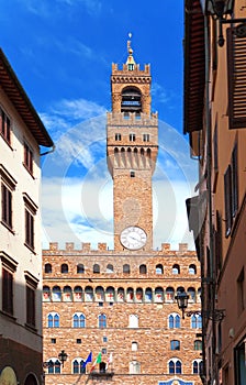 The clock tower of the Old Palace (Palazzo Vecchio) in Signoria Square, Florence (Italy) against the blue sky