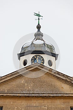Clock tower with weather vane and pediment in the snow