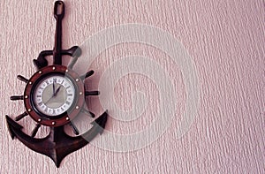 Clock in wood anchor on pink wallpaper background.