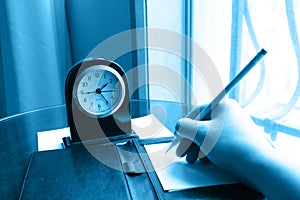 Clock and writing hand on note