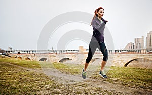 Clocking some workout time. a sporty young woman listening to music while running alongside the city.