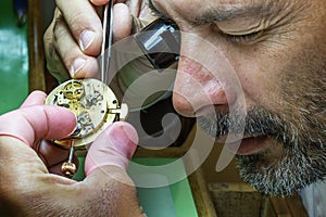 Clockmaker repairs antique golden pocket watch in his laboratory