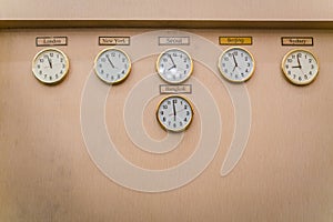 Clocks shows different time zones on old wall .