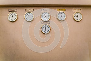 Clocks shows different time zones on old wall .