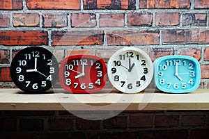 Clocks with time zone of different country on wooden shelves and brick wall background