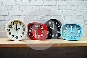 Clocks with time zone of different country on wooden shelves and white brick wall background