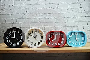 Clocks with time zone of different country on wooden shelves and white brick wall background