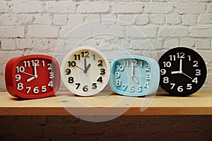 Clocks with time zone of different country on wooden shelves and white brick wall background