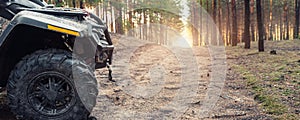 Clode-up side of ATV awd quadbike motorcycle profile view dirt country forest road beautiful nature morning sunrise