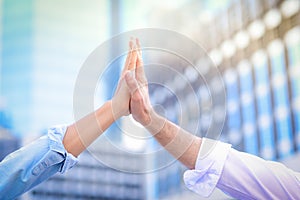 Cloe up of both hands giving high five to each other With a blurred building background