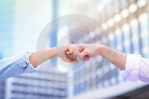 Cloe up of two hands businessman making a first bump  With a blurred building background