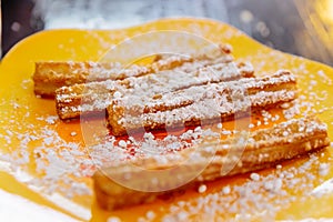 Cloes up Churros topping with icing sugar served with nutella sauce on yellow plate