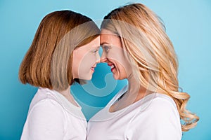Cloeup profile photo of two people beautiful mommy lady small little daughter blonds look eyes leaning head to head wear photo