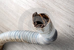 Clogged plastic corrugated drain pipe lies on the floor.