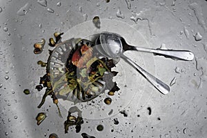 Clogged strainer in the sink and spoon in the sink