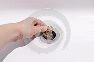 Clogs In Drain, Hair Loss, Hair Fall. Human Hand Pulls Big Tuft Of Blond Hair In White