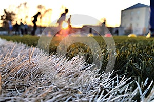 Close the artificial lawn with a white stripe and blurred football against the background
