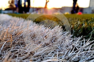 Close the artificial lawn with a white stripe and blurred football against the background