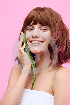 a close beauty portrait of a beautiful sophisticated woman with a beautiful styling, holding an aloe leaf near her face