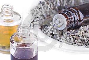 Close on bottles of oil in a bowl full of dried lavender and other bottles