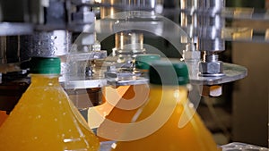 Close caps on automatic conveyor line on plastic bottles in production of juice.