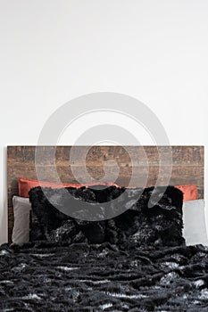 Close capture of black furry blanket on the wooden bed