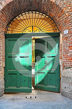close detail of an ancient portal made of green woodden door and wrought iron