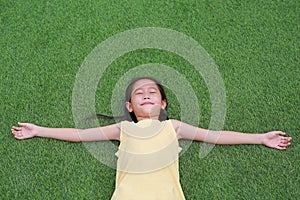 Close eyes little Asian child girl with two ponytail hair lying on green grass in the garden